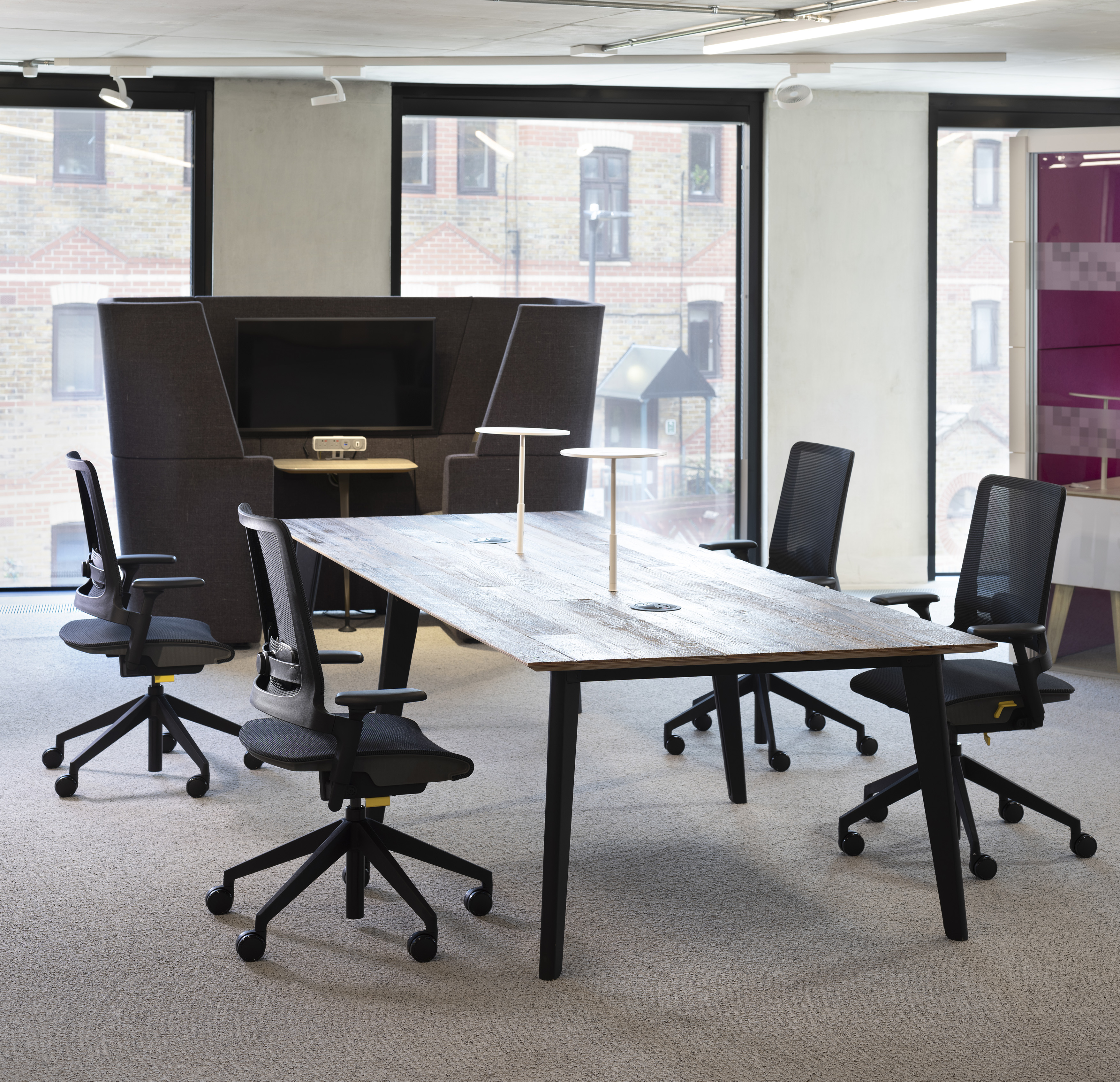 Black office chairs positioned around a brown meeting table